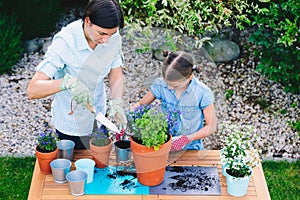 Mother and daughter planting flowers in pots in the garden - concept of working together, closeness