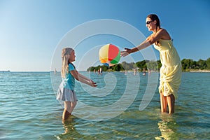 Mother and daughter playing with ball on beach