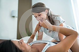 Mother and daughter playing on bed