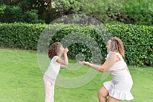 Mother and daughter playing with bubbles in a park