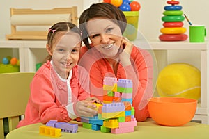 Mother with daughter are playing with building bricks in preschool