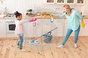 Mother and daughter playing and having fun while cleaning