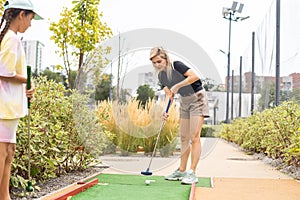 mother and daughter playing mini golf, children enjoying summer vacation