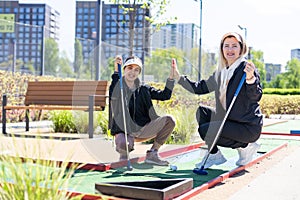 mother and daughter playing mini golf, children enjoying summer vacation