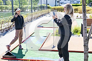 mother and daughter playing mini golf, children enjoying summer vacation