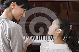 Mother and daughter playing the piano