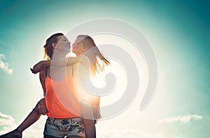 Mother and daughter playing together outdoor - Happy family piggyback at sunset