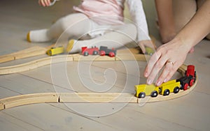 Mother and daughter playing together with toys indoor at home. Mom helps her baby girl. Family lifestyle concept