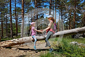 Mother and daughter playing on tree trunk in a forest