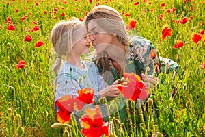 Mother with daughter on the poppies meadow. Beautiful mom and daughter on a poppy field outdoor. Poppies flowers.