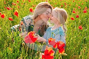 Mother with daughter on the poppies meadow. Beautiful mom and daughter on a poppy field outdoor. Poppies flowers.