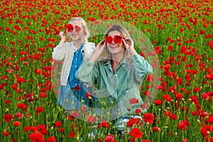 Mother with daughter on the poppies meadow. Beautiful mom and daughter on a poppy field outdoor. Poppies flowers. Happy