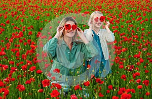 Mother with daughter on the poppies meadow. Beautiful mom and daughter on a poppy field outdoor. Poppies flowers. Happy