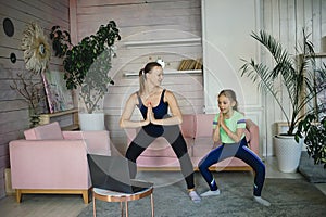 Mother and daughter practicing online yoga lesson at home