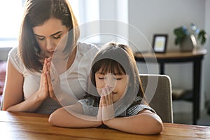 Mother with daughter praying at home