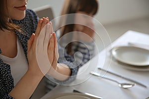 Mother with daughter praying before meal at home