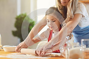 Mother and daughter prepare flour baked goods on a table in the kitchen. Happy mother`s day