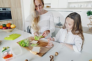 Mother daughter preparing school lunch home kitchen