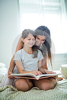 Mother and daughter reading book on bed