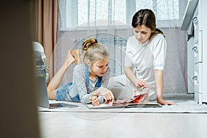 Mother and daughter reading book on the floor at home in the living room