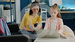 Mother and daughter reading book together and doing homework