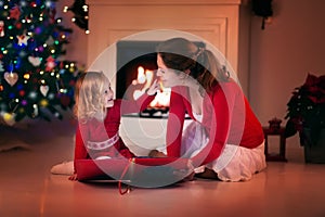 Mother and daughter reading on Christmas eve at fire place