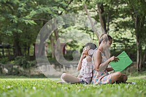 Mother and daughter reading a fairytale to her daughter listen sound with headphone