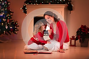 Mother and daughter reading at fire place on Christmas eve