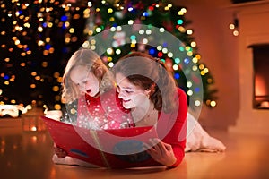 Mother and daughter reading at fire place on Christmas eve