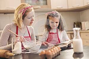 Mother and daughter reading instructions from a cookbook