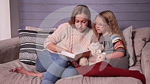 Mother and daughter reading story at home together