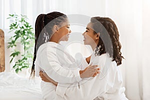 Mother Daughter Relationship. Little Girl And Mom In Bathrobes Embracing At Home