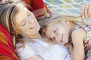 Mother And Daughter Relaxing In Garden Hammock Together