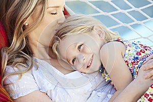 Mother And Daughter Relaxing In Garden Hammock Together