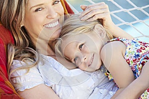 Mother And Daughter Relaxing In Garden Hammock Together