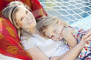 Mother And Daughter Relaxing In Garden Hammock Together