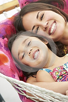 Mother And Daughter Relaxing In Garden Hammock Together