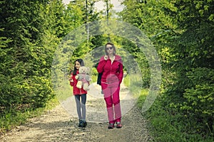 Mother and daughter on the relaxing spring walk through the green forest