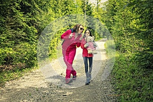 Mother and daughter on the relaxing spring walk through the green forest