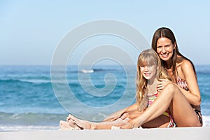 Mother And Daughter Relaxing Together On Beach