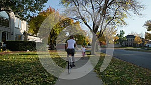 Mother and daughter ride bicycles in a park and on a suburban street on a sunny day. Slow motion wide footage