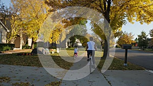 Mother and daughter ride bicycles in a park and on a suburban street on a sunny day. Slow motion wide shot footage