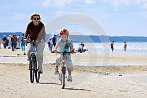 Mother and daughter riding along the beach