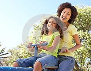 Mother And Daughter Riding On Seesaw In Park photo