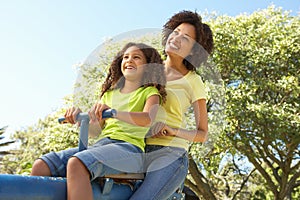 Mother And Daughter Riding On Seesaw In Park photo