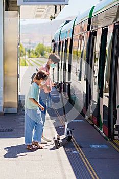 Mother and daughter riding on a train with an electronic scooter