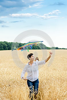 Mother and daughter run in a wheat field with a kite in the summer. Well-planned and active weekend. Happy childhood.