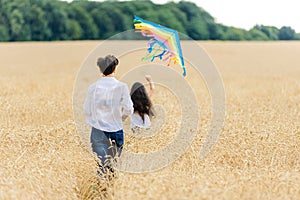 Mother and daughter run in a wheat field with a kite in the summer. Well-planned and active weekend. Happy childhood.