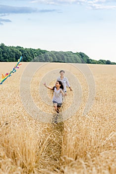 Mother and daughter run in a wheat field with a kite in the summer. Well-planned and active weekend. Happy childhood.