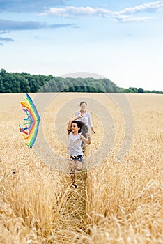 Mother and daughter run in a wheat field with a kite in the summer. Well-planned and active weekend. Happy childhood.